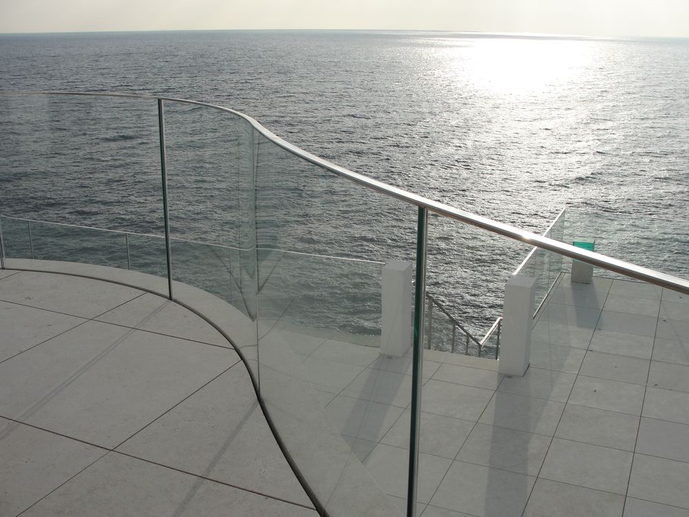 Garde-corps en inox et verre suivant la courbe d’une terrasse face à la mer